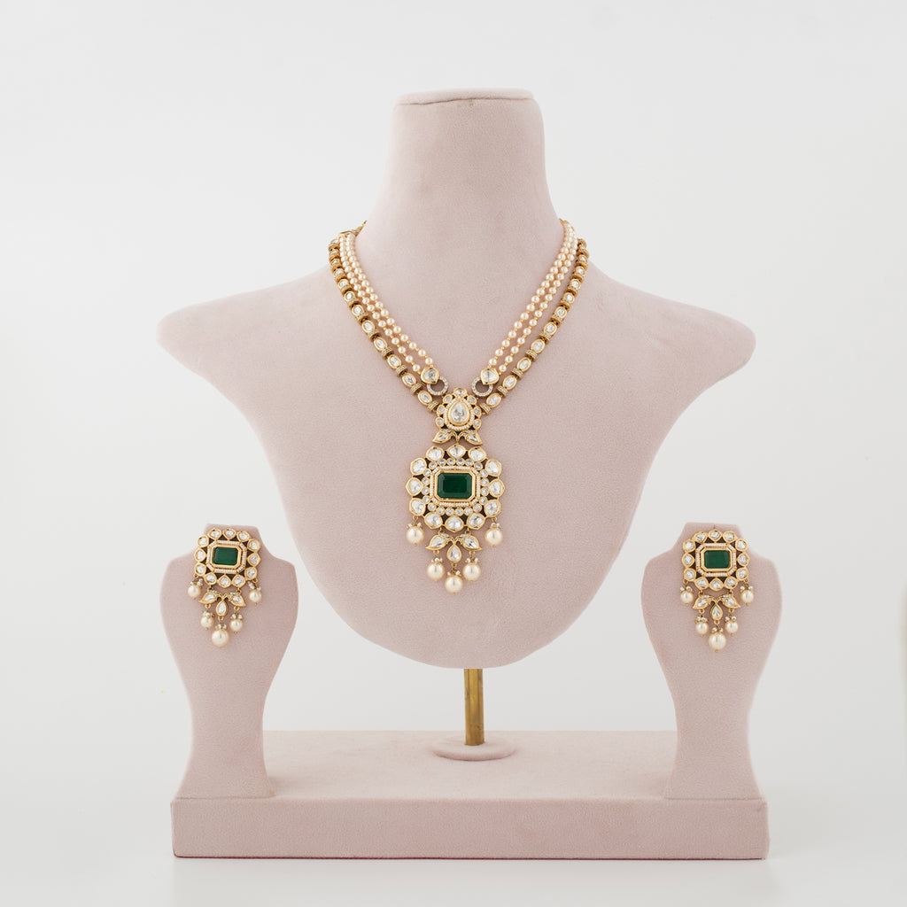 Emerald-green artificial necklace set with matching earrings displayed on a jewellery stand