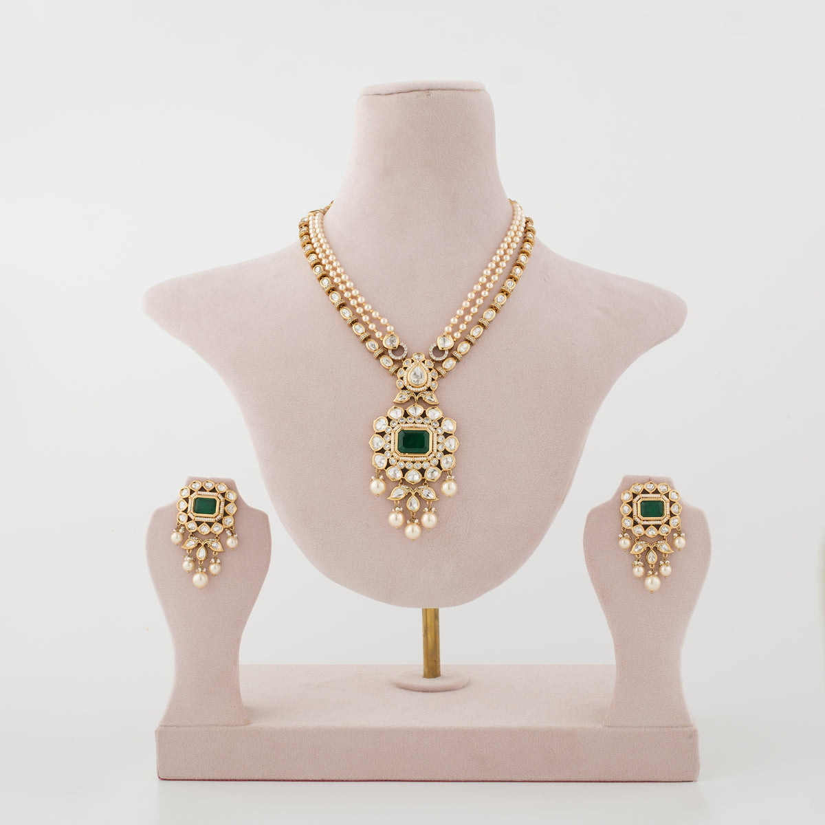Emerald-green artificial necklace set with matching earrings displayed on a jewellery stand